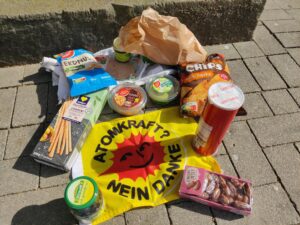 Auf Steinen eines Bürgersteigs liegt eine Anti-Atom-Fahne auf der verschiedene Snacks liegen.